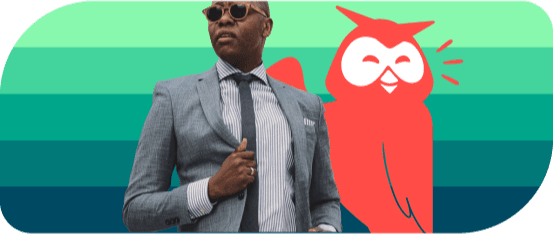 A man in a suit with sunglasses in posing beside Owly