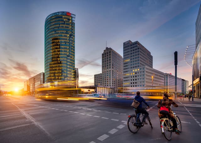 a city street with people riding bicycles and buildings in the background