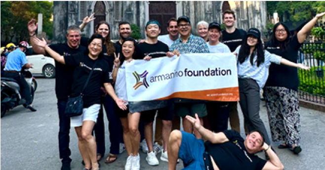 Foto grupal exterior de miembros de la Fundación Armanino vitoreando y sosteniendo una pancarta de Armanino.